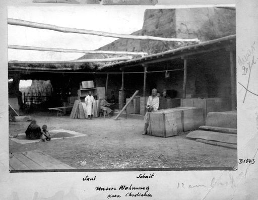 B1043: Der Wirt Saut und der Tischler Schait (?) im Innenhof des Bauern Sa'ut vor der nördlichen Stadtmauer mit großen Kisten (B_1043_Kara_Kodscha_Unsere_Wohnung_pos.jpg)