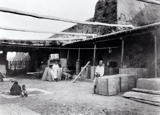 B 1043: Der Wirt Saut und der Tischler Schait (?) im Innenhof des Bauern Sa'ut vor der nördlichen Stadtmauer mit großen Kisten