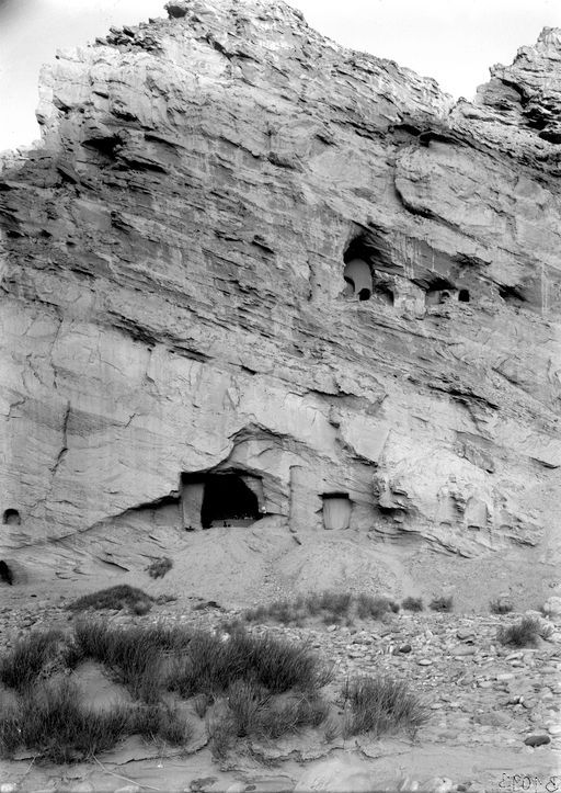 B1093: Felswand mit Höhlenanlagen. Zu sehen sind Anzeichen von Grabungsarbeiten in der unteren Höhle (4), von den oberen drei Höhlen (5-7?) sind nur die hinteren Wände der Cellae erhalten. (B_1093_Kum.jpg)