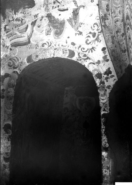 B1183: Blick auf eine Kultbildwand: links neben der Mandorla des Buddha wird der Eingang in den linken Gang mit einer Blütenbordüre geschmückt, darüber befinden sich Streublüten und Wolken. Im Gang sind stehende Buddhas und Bodhisattvas sichtbar. (B_1183_IB_8832_Kum38.jpg)