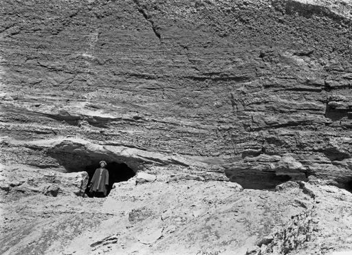 B1225: Einheimischer steht vor der Felswand mit Höhlenanlage (B_1225_Kum_2Schlucht.jpg)