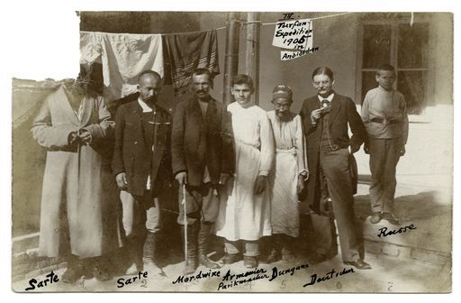B 1502a: Postkarte des Fotos B 1502 mit Beschriftung: Grünwedel in einer Gruppe von Personen aus dem Haushalt seines Gastgebers Oberst Saizof im 'Hotel Witte'; 1 Dungane, 2 Sarten, 1 Mordwine, 1 Armenier, 1 Russe