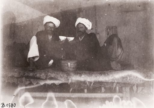 B1580: Zwei beturbante Männer mit Trinkschalen auf einem Holzbett ; Le Coq und Bartus (Turfan_II_42_B_1580.jpg)