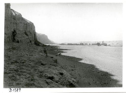 B1589: Höhenzug mit steiler Felswand und Höhleneingängen auf der einen Seite einer Flusslandschaft mit Bauernhaus; Höhenzug an dem anderen Ufer (Bezeichnung 'Kucha'). Wenn Kumtura, dann am Südende der Anlage mit Blick nach Süden. Vielleicht ist es aber auch Shorchuk (?) (B_1589_pos.jpg)