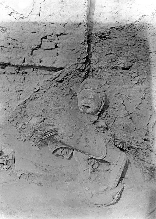 B1603: Reste der Lehmskulptur eines Dämons vor einer Ziegelmauer. (B_1603_xxx_Figur.jpg)