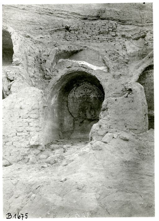 B 1675: Gemauerte Cella mit Gewölbe und Resten eines sitzenden Buddha mit großer flammender Mandorla, Reste von Wandmalerei. Die Konstruktion der Zellenreihe mit gemauerten Doppelgewölben gegen den gewachsenen Fels ist gut zusehen.