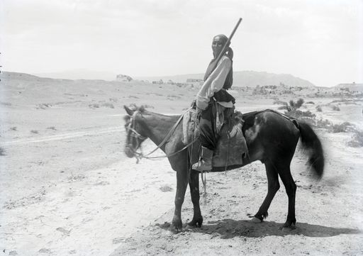 B 1706: Reiter mit Gewehr (Ho pa, unser mongolischer Soldat (Pohrt), örtlicher Begleiter der III.Expedition) vor der Ruinenanlage. Im Hintergrund der Gebirgszug mit den Höhlen.