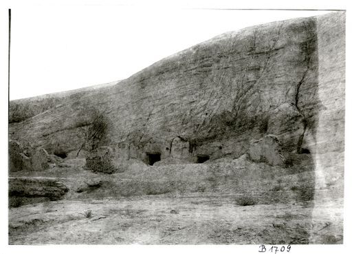 B 1709: Die 5 Höhleneingänge der 2. Anlage von Murtuk hinter der Berglehne, Reste von Ziegelbauten der Vorräume