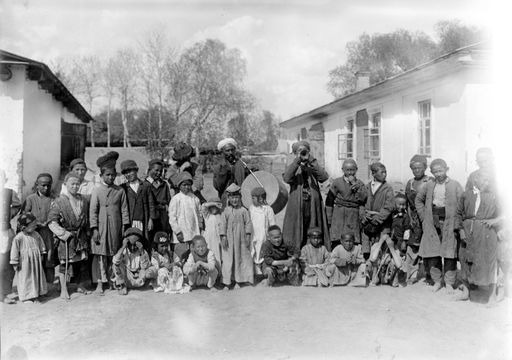 B 1811: Gruppe von Kindern und Männern mit Trompete und Pauke vor Schulgebäude (?)
