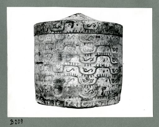 B209: Runde hölzerne Aschenurne, mit Deckel, bemalt: gelber Grund mit geflügelten Tieren grau bemalt. (B_209_III_7649ab_pos.jpg)