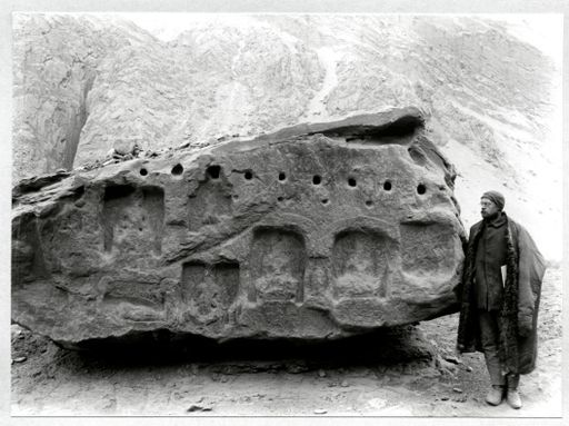 B880: Behauener Fels mit Balkenlöchern und Reliefresten in quadratischen Vertiefungen der Buddha-Nischen, daneben A. Grünwedel, vergleichbarer Fels B 875. (B_880_Albert_Gruenwedel_an_Felswand_pos.jpg)