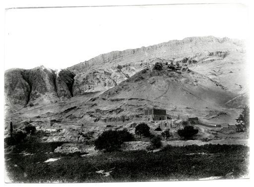 B 946: Blick vom Dorf über das Tal und hin zum östlichen Gebirgszug mit einem Traubenhaus davor.