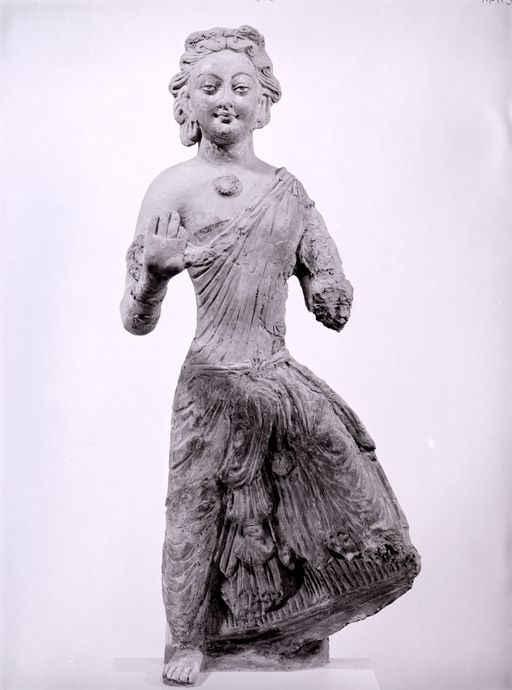 C 147: Devatā (Gottheit), stehendin Abhayamudrā und mit einem angewinkelten Knie, eine antike Maske in der Krone, Frontalansicht