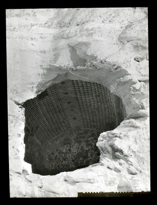 T 190: Blick von unten durch eine zerstörte Front in eine Cella, wo neben dem Zenithstreifen tausend kleine Buddhas an der Decke dargestellt sind. An der Kultbildwand befindet sich ein Maitreya.