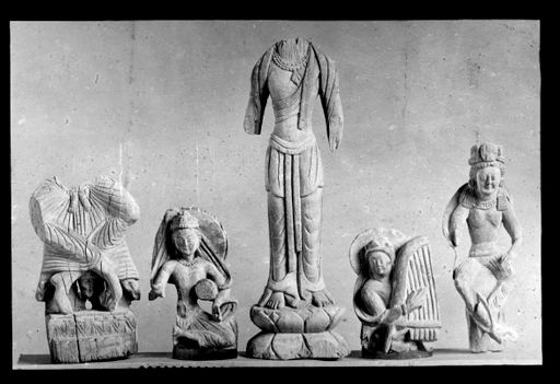 T 411: Fünf verschiedene, kleine fragmentarische Holzstatuetten: Unterkörper von einem Maitreya mit gekreuzten beinen, Teile eine sitzenden Musikanten mit Trommel, Torso eines stehenden Bodhisattva auf Lotos, Oberkörper eines Harfenspielers, fast kpmplette Statuette eines Maitreya mit gekreuzten Beinen.