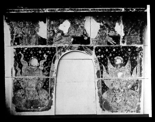 T 565: Zwei Mönche mit Schulterflammen zu Seiten eine Aussparung für eine Nische, darüber fliegende Gottheiten