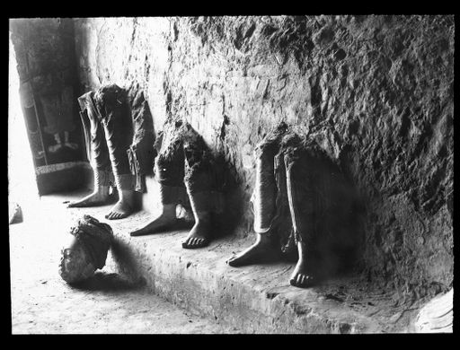 T 650: Beine von Buddhastatuen in ungefährer Lebensgröße auf einem niedrigen Podest, Kopf auf dem Boden