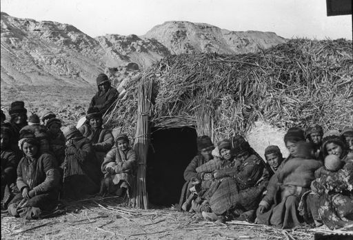 T 68: Gruppe von Frauen und Kindern vor der Hütte der Expedition, Aufschrift: unser Hotel Riz